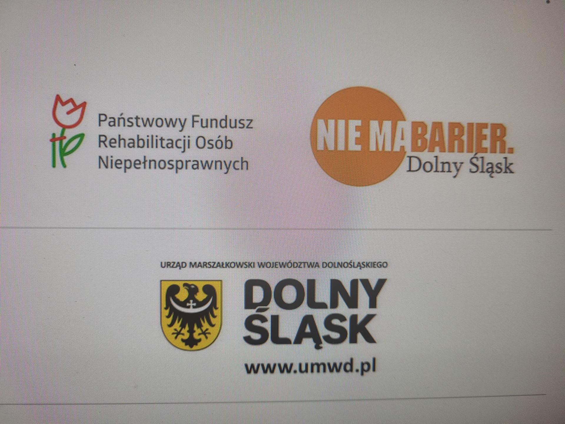 Zdjęcie przedstawia logo Państwowego Funduszu Rehabilitacji Osób Niepełnosprawnych . Sygnet przedstawia kwiat, który jest „osłabiony”. Dzięki podporze rozkwita. Kwiat symbolizuje osobę niepełnosprawną, podpora zaś - wsparcie ze strony Państwowego Funduszu Rehabilitacji Osób .
Na drugim zdjęciu poniżej widać w pomarańczowym kółku napis- nie ma, dalej na pomarańczowo napis barier. Poniżej w kolorze czarnym widnieje napis Dolny Śląsk.